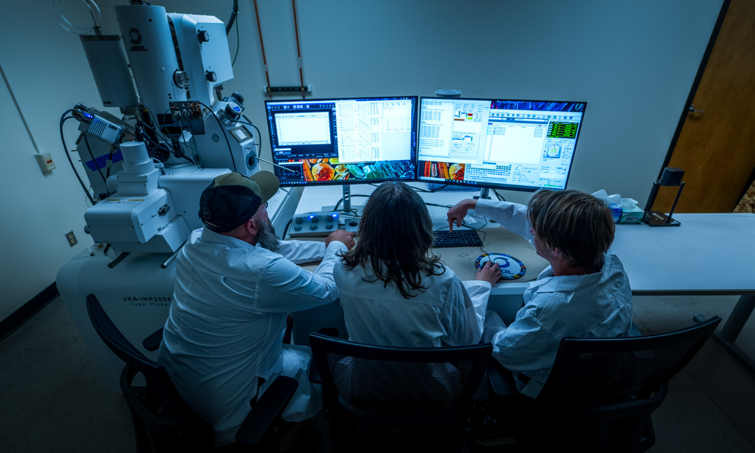 three people look at computer screens with the hyper probe in the background
