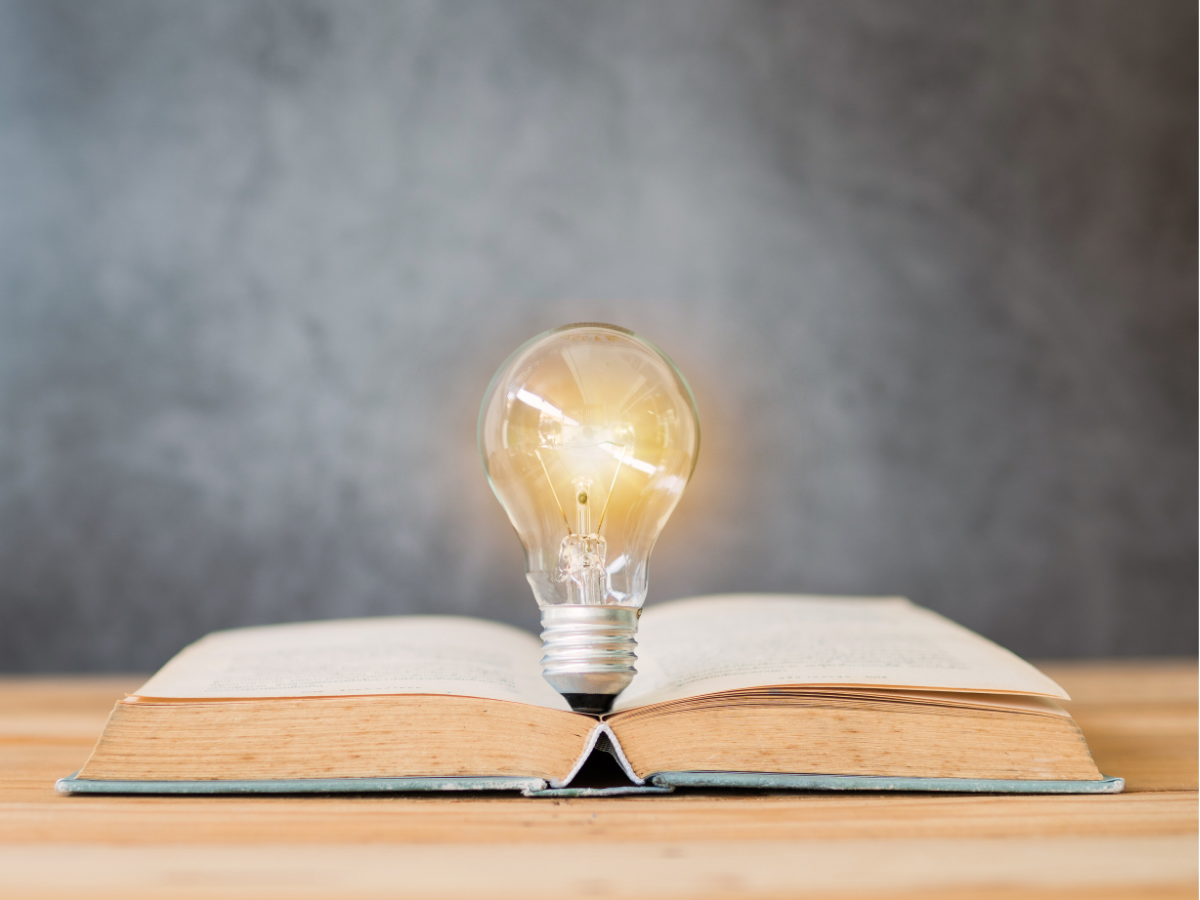 Photo of an open book with a lightbulb in the middle.