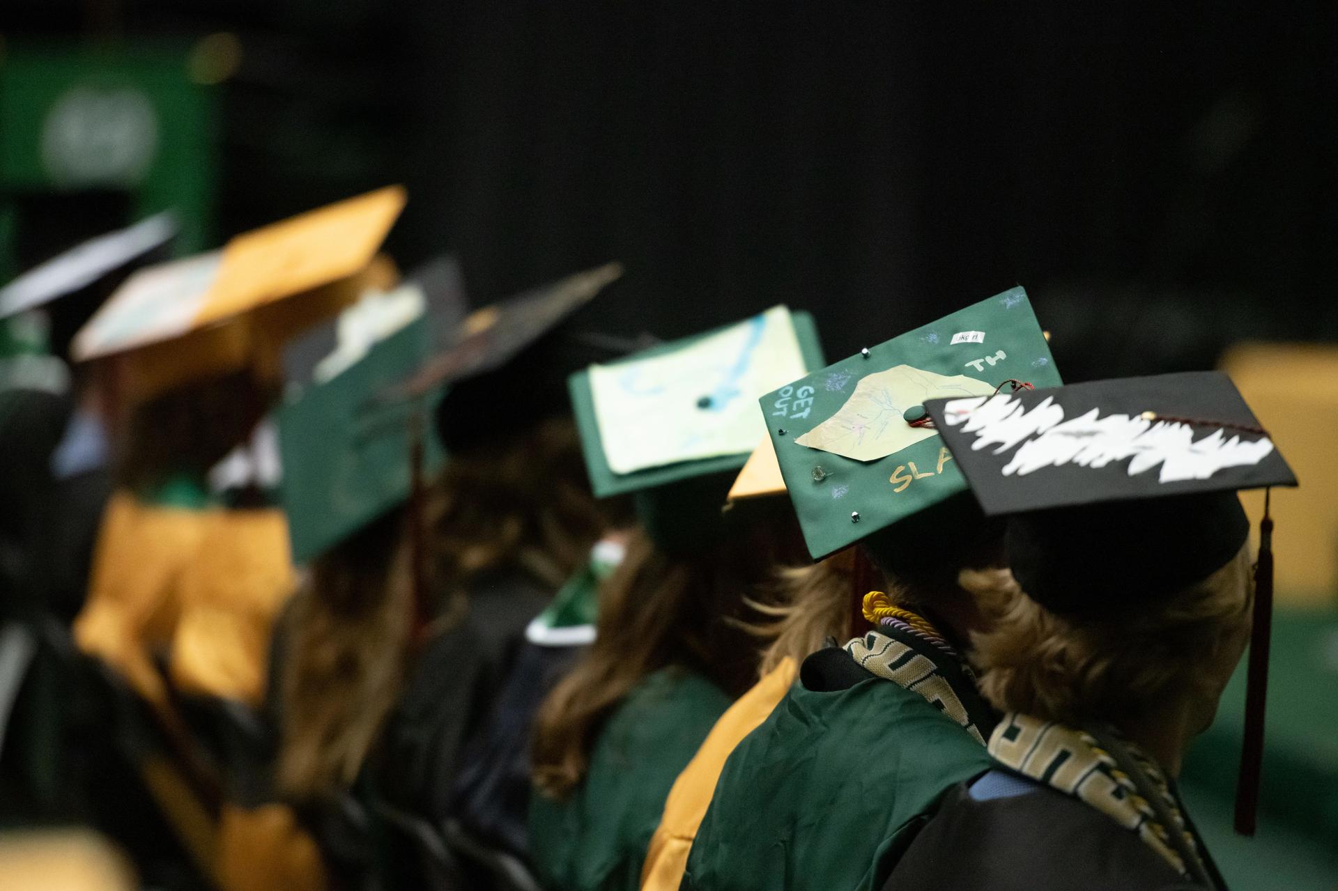 Students sit wearing mortar boards at graduation