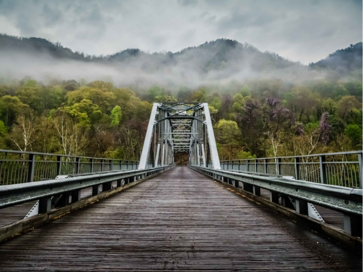 A bridge below a foggy mountain range.