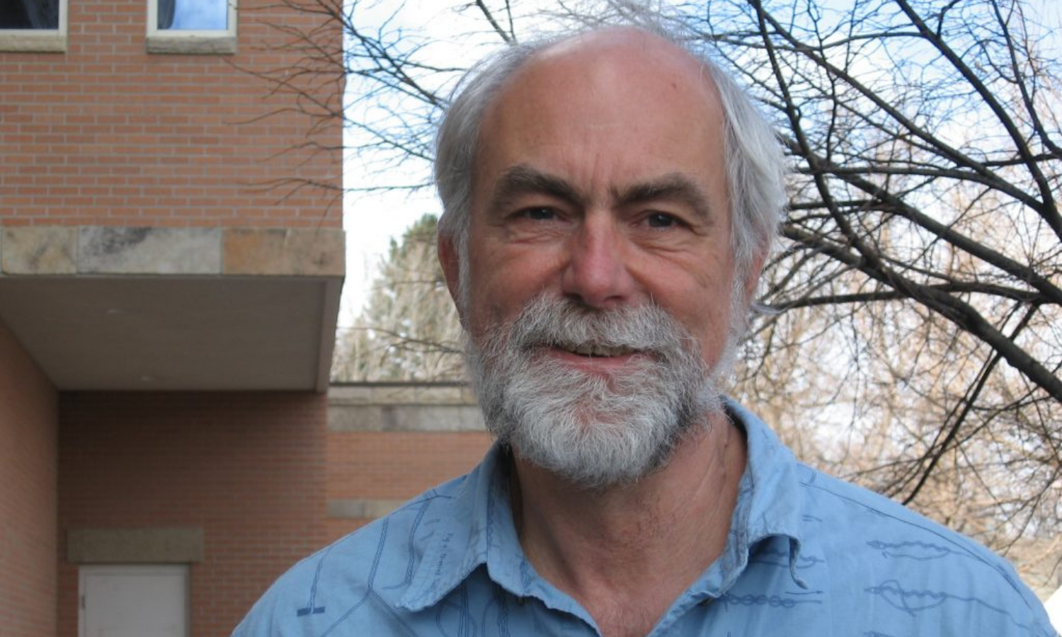 Bill Parton smiles in front of the NREL building. 