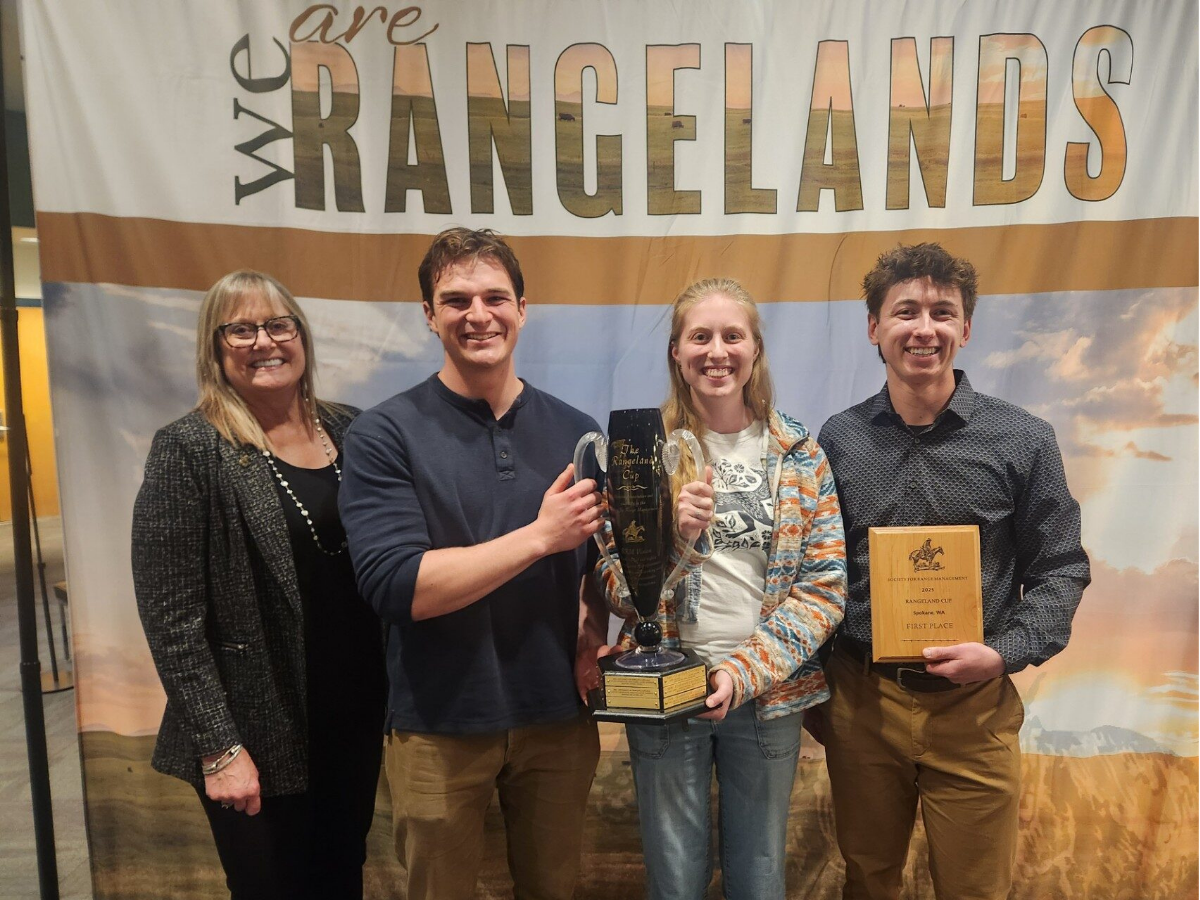 Four people hold up the trophy and plaque from the Rangeland Cup. 