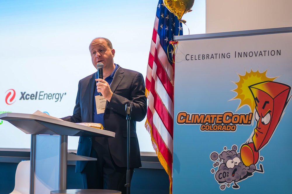 photo of Governor Jared Polis speaking at a past ClimateCon!