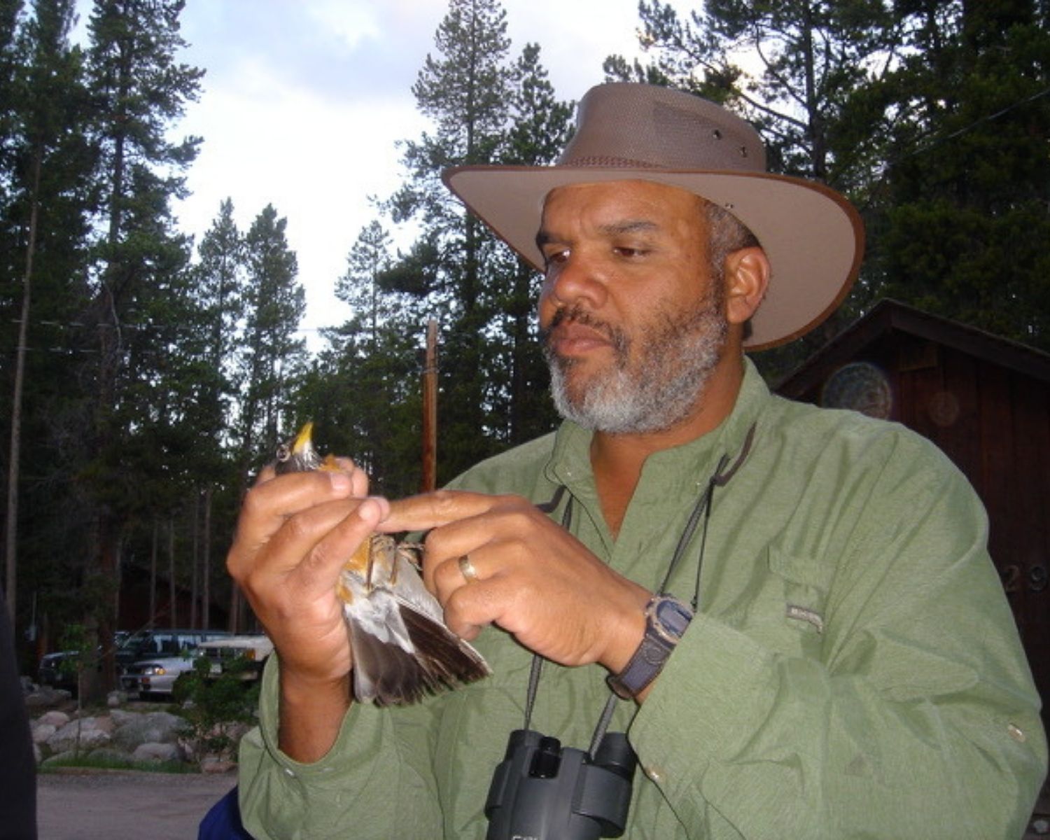 photo of Ken Wilson holding a bird, teaching students outdoors