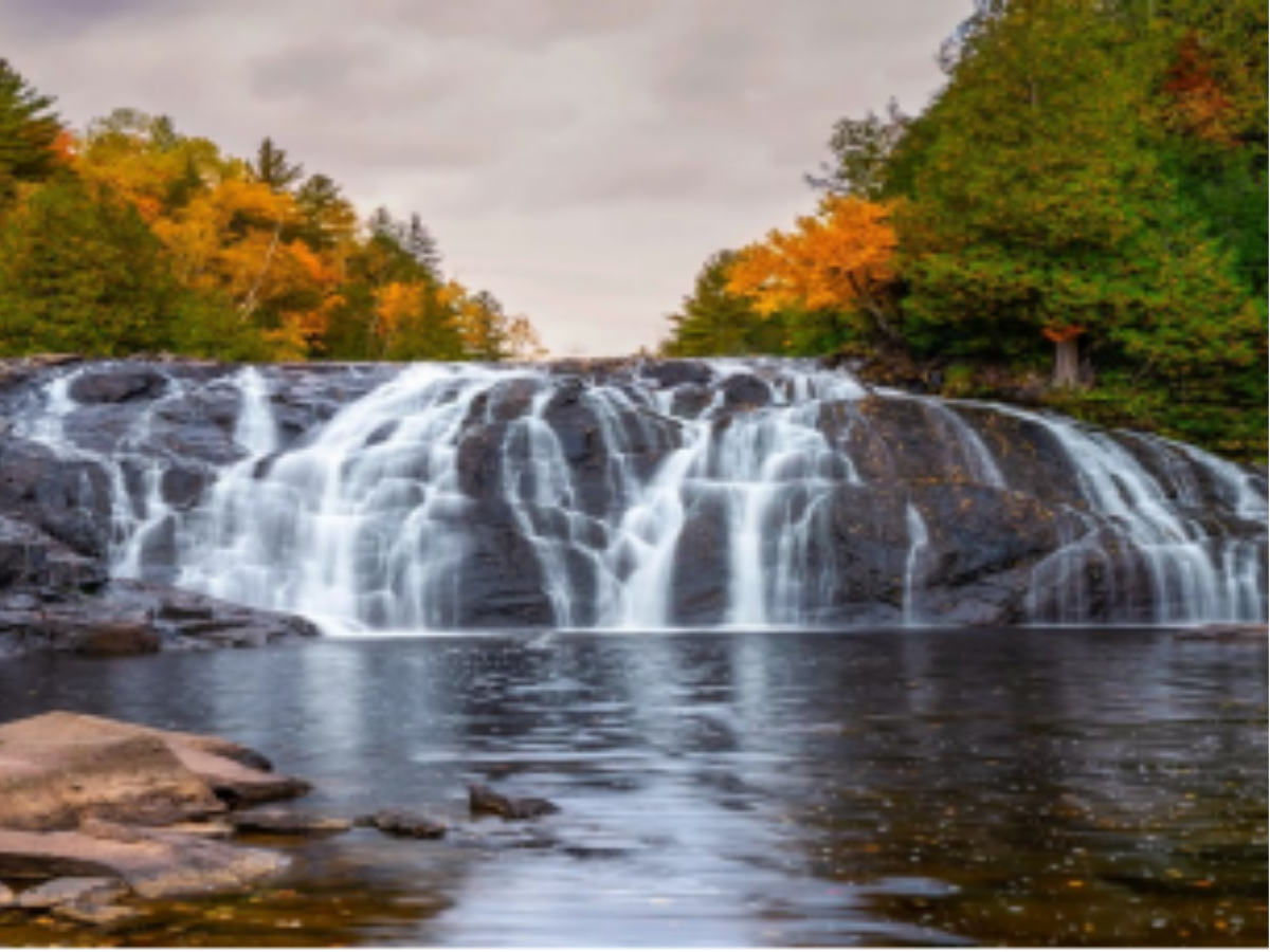 Water flows off of large rocks into a river. 