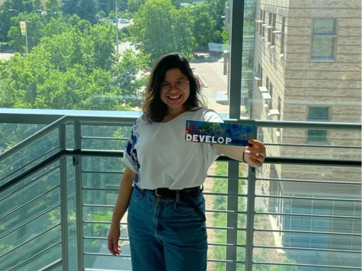 Sheyla Gaviota Rios holds a bookmark with the word DEVELOP. 
