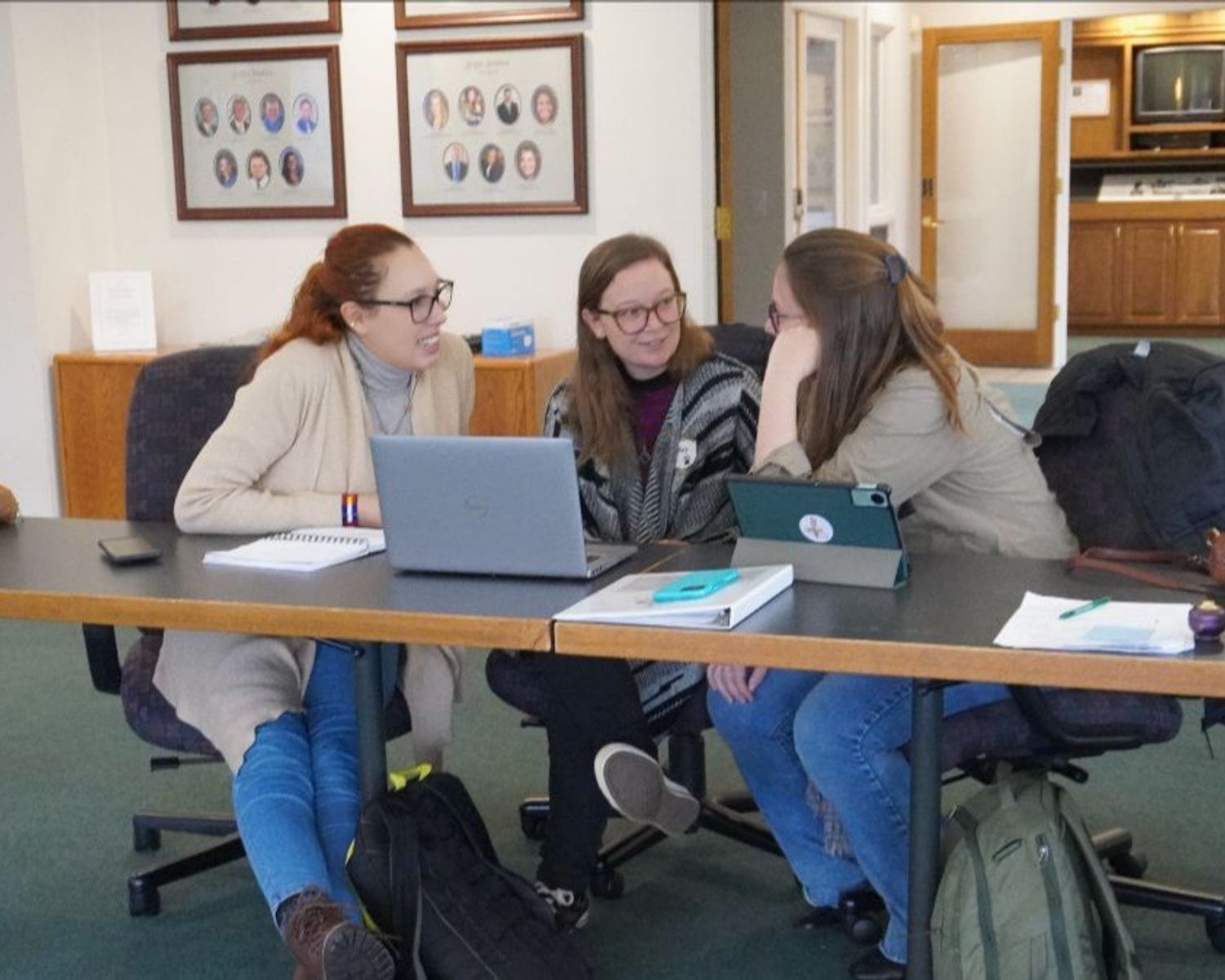 three people talk to each other at a table, including Aireona