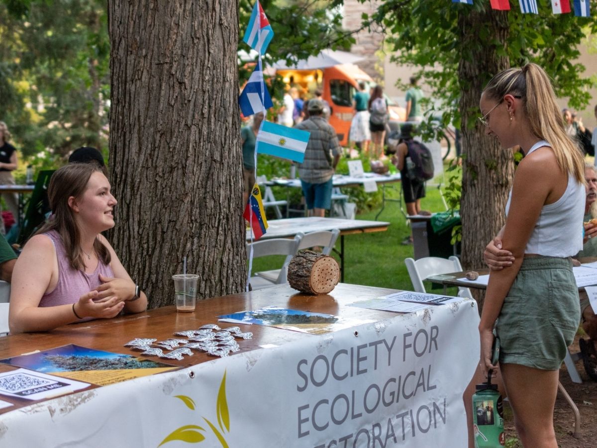 A student with the Society for Ecological Restoration speaks with another student. 
