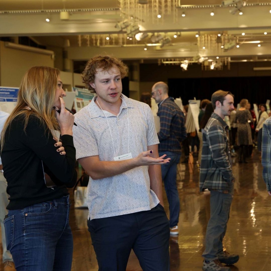 Two people discuss a poster at the 2024 Graduate Student Showcase.