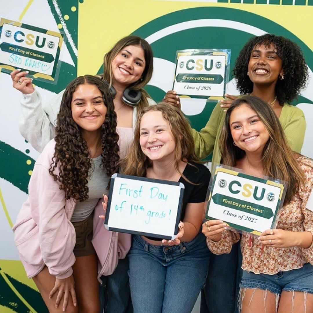 photo of people smiling and standing against a CSU background