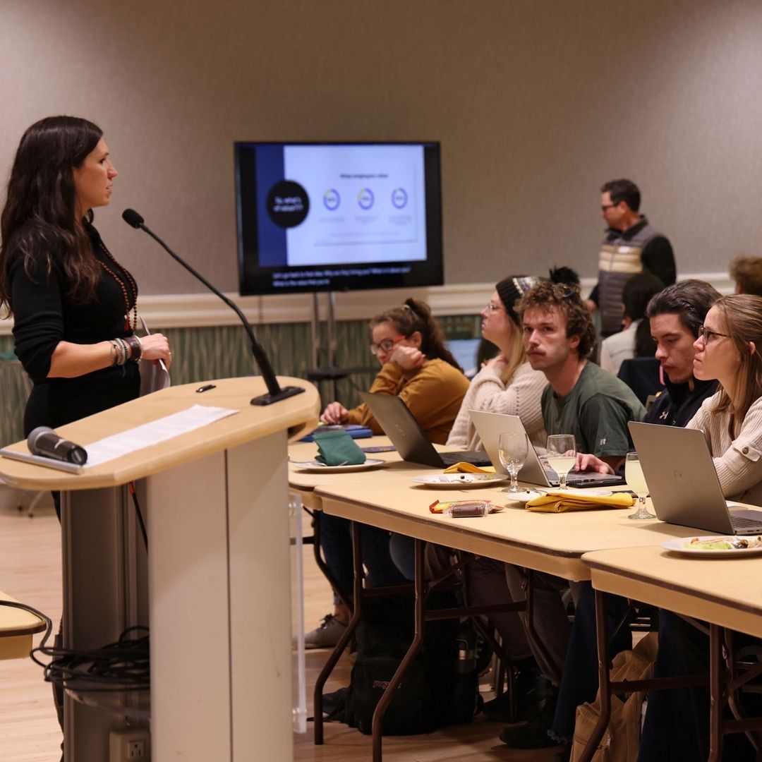 A person stands at a podium talking to a classroom of students.