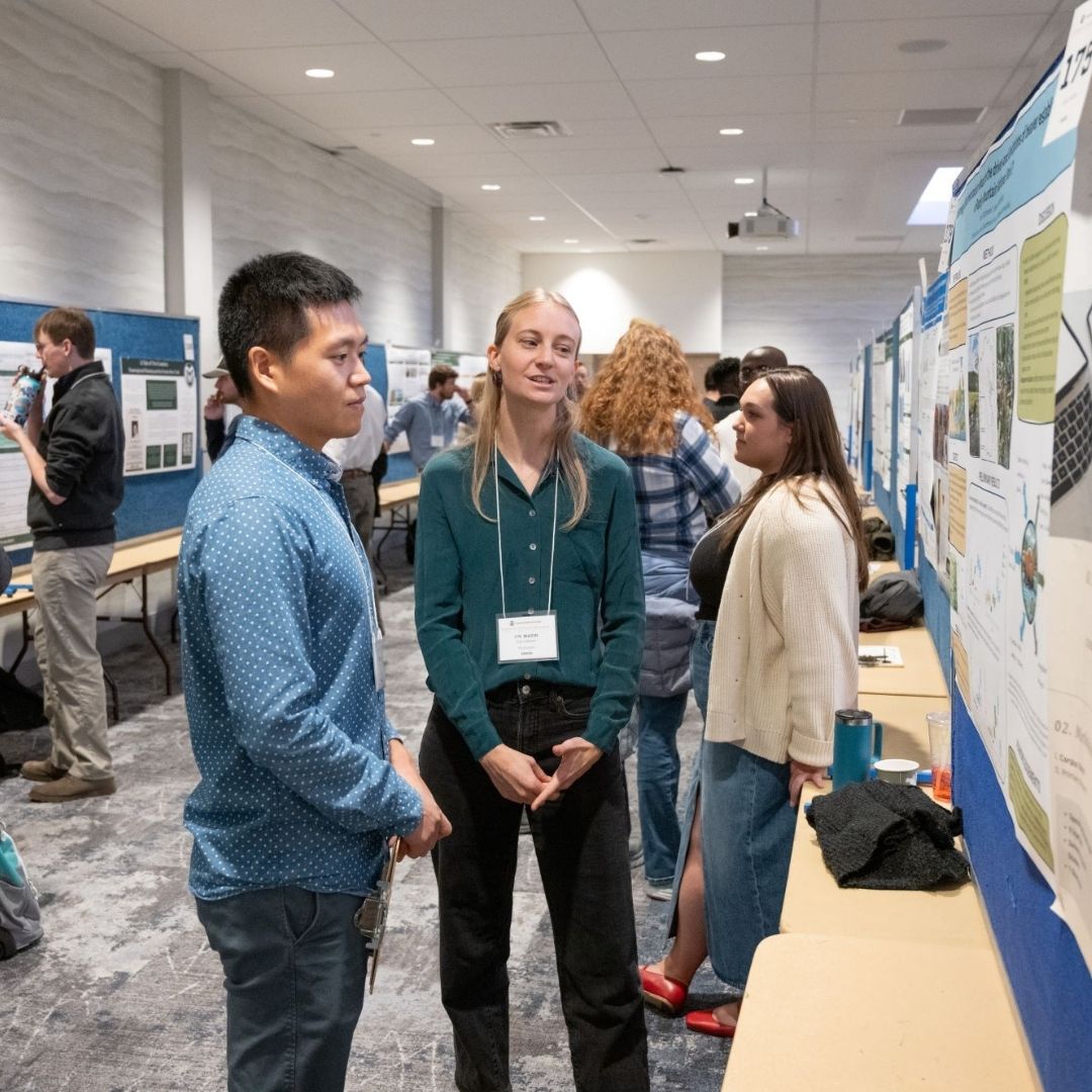 Two people discuss a poster at the 2024 Graduate Student Showcase.