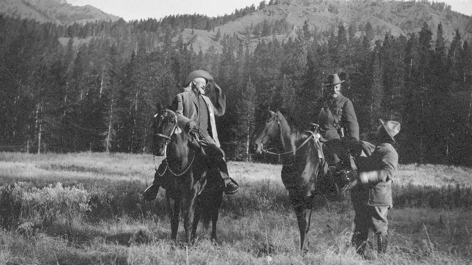 black and white photo of three people, two of whom are on horse back