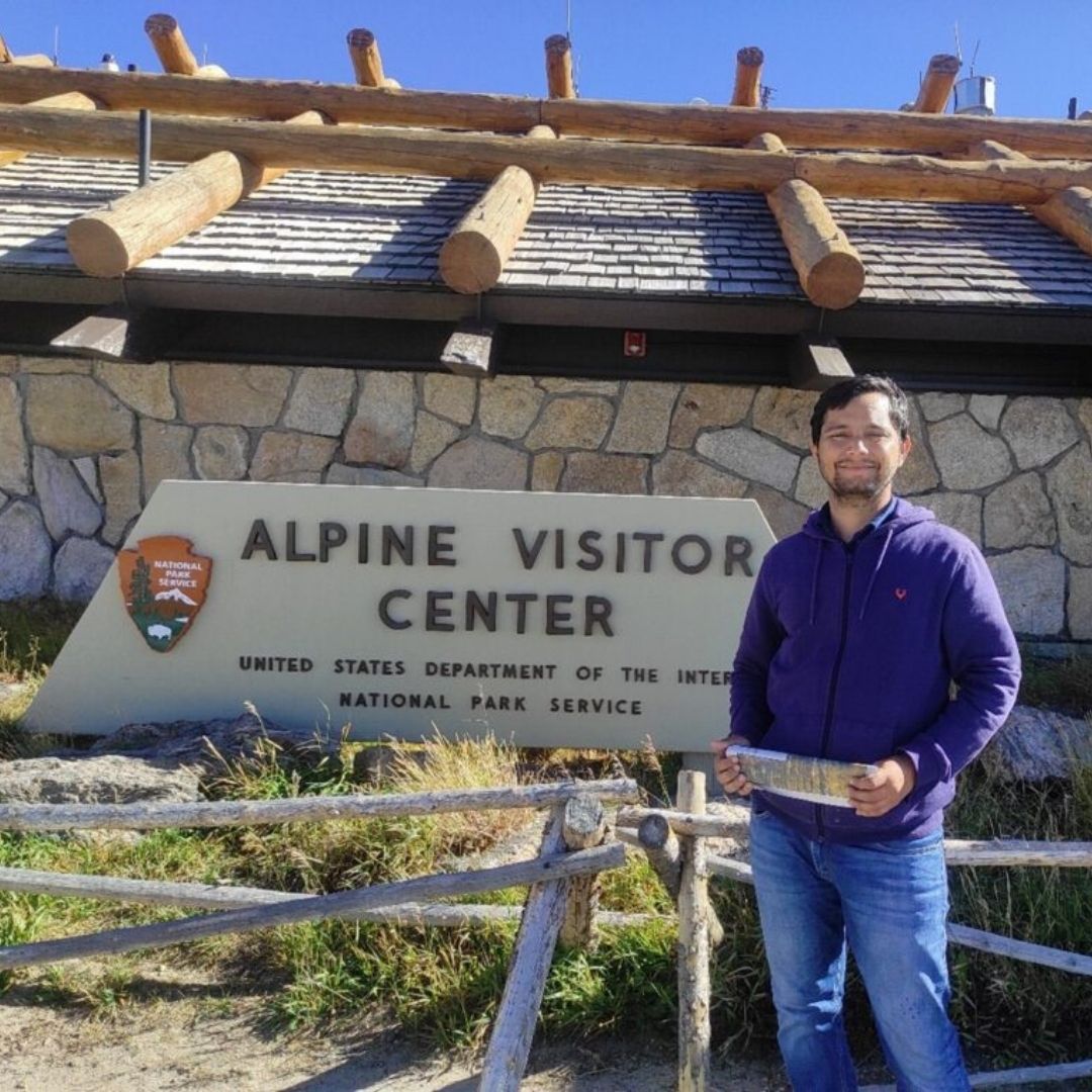 Ajay Devda stands in front of the Alpine Visitor Center sign. 