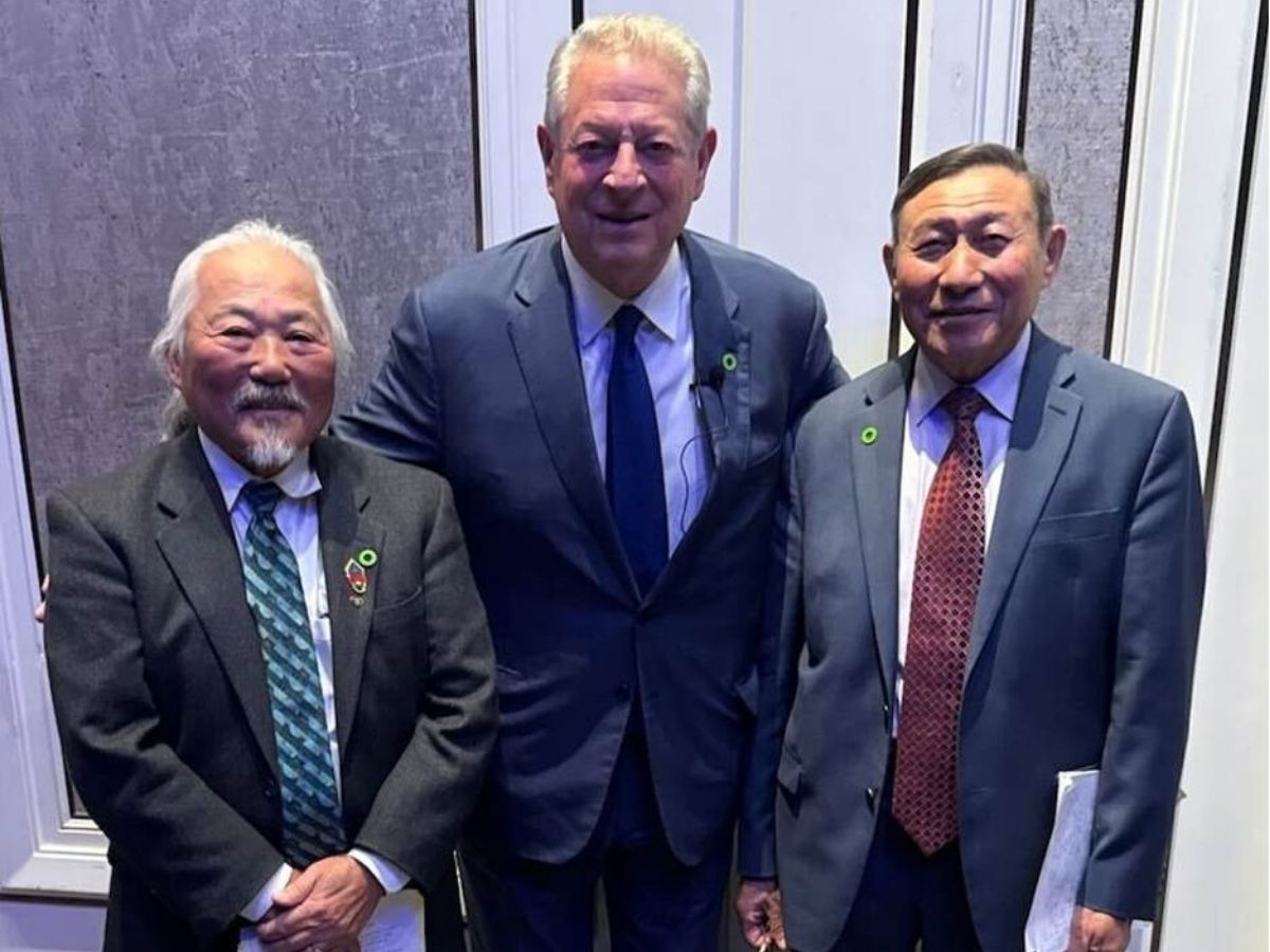 Three people in suits and ties stand together posing for a picture. 