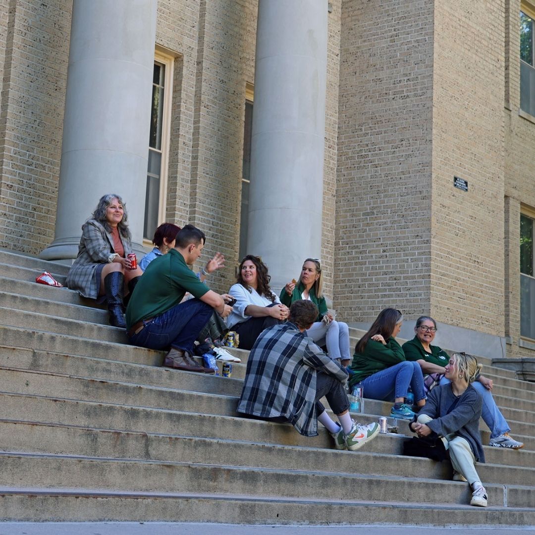 Several people sit on the stairs of the CSU administration building talking