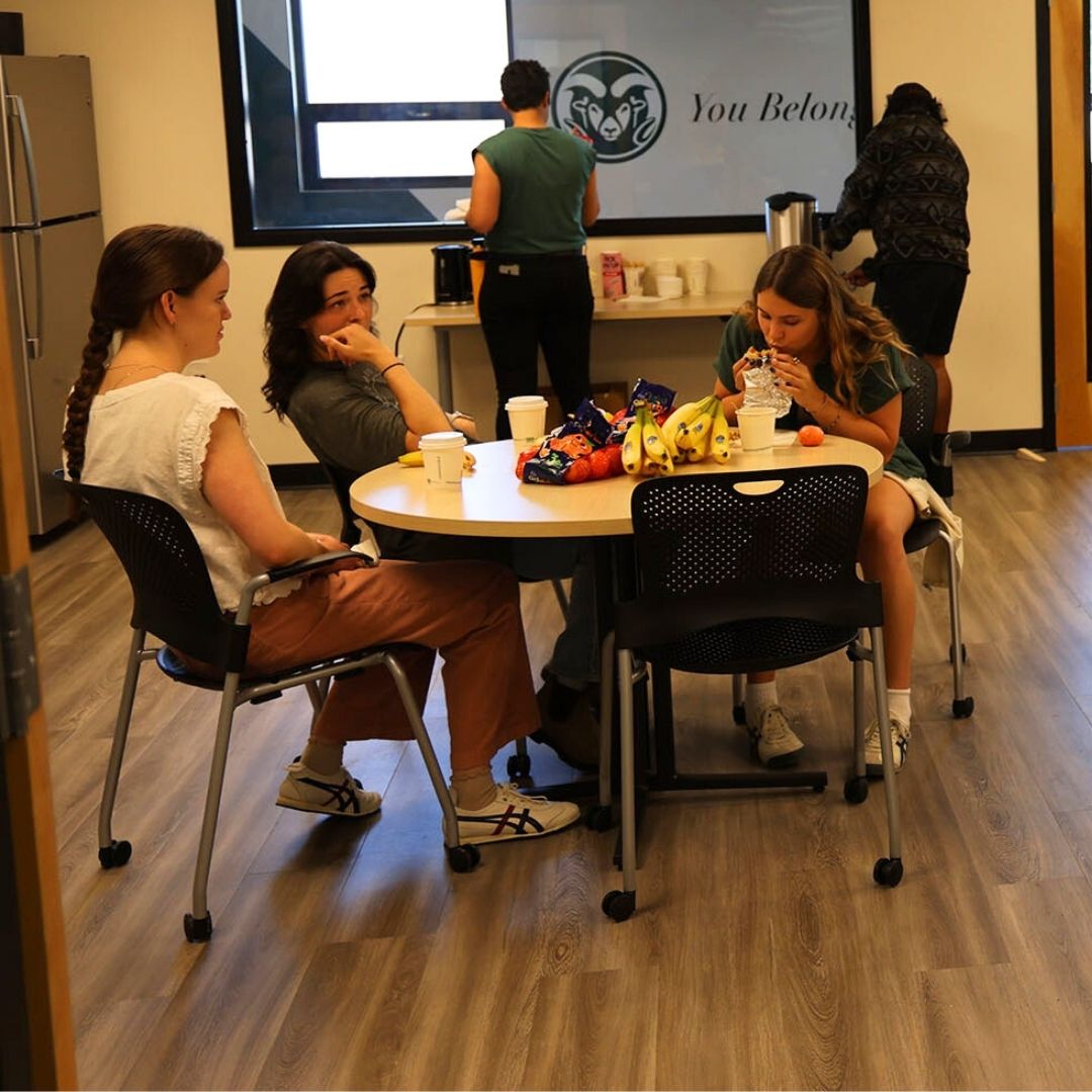 Three people sit at a table talking in the GradSpace