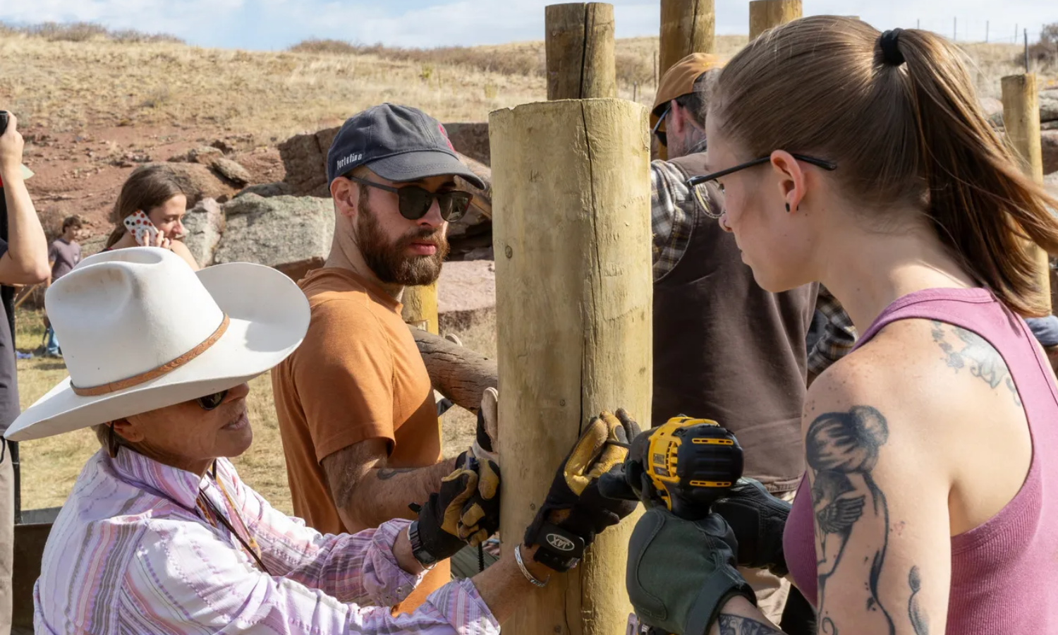 three people using tools to erect a pole