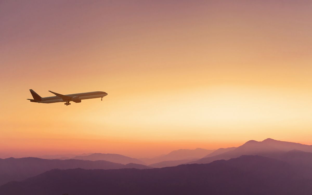 plane flying over the mountains at sunset