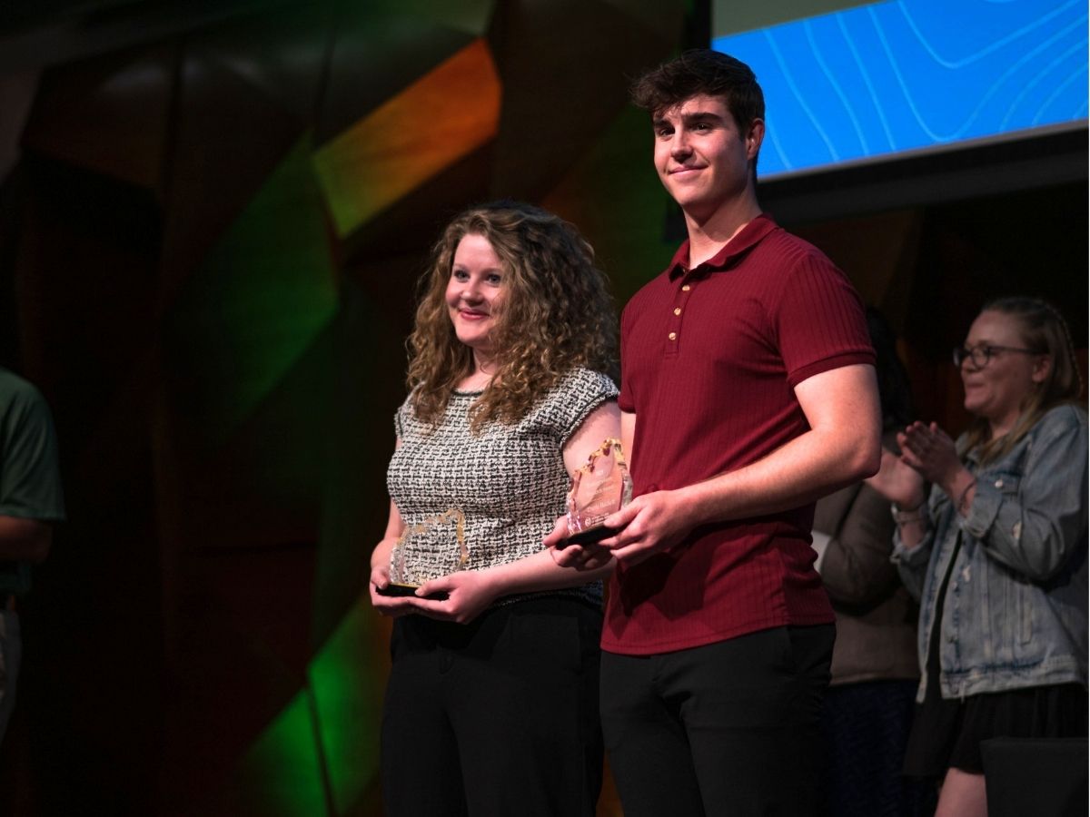 Two people receive awards on stage