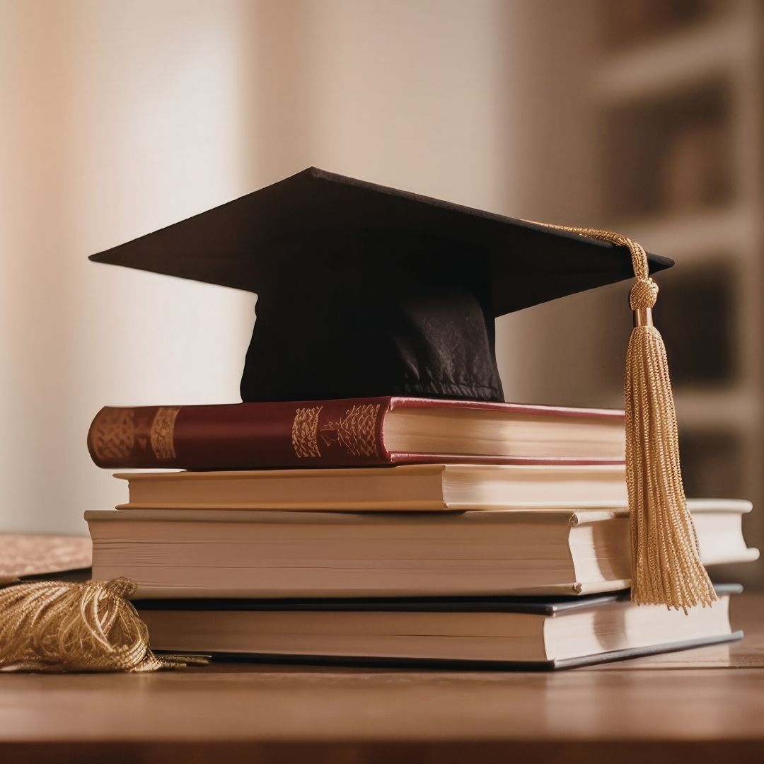 A mortar board sits on top of a stack of books