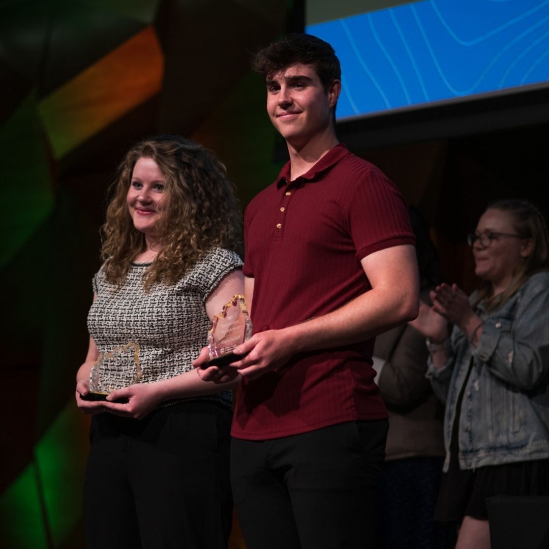 Two students hold awards on stage