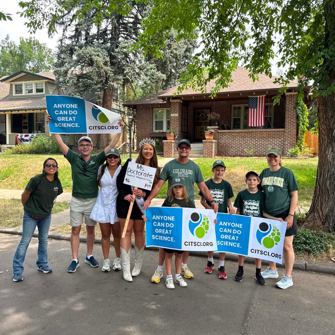 A group of people pose for a picture holding CitSci signs. 