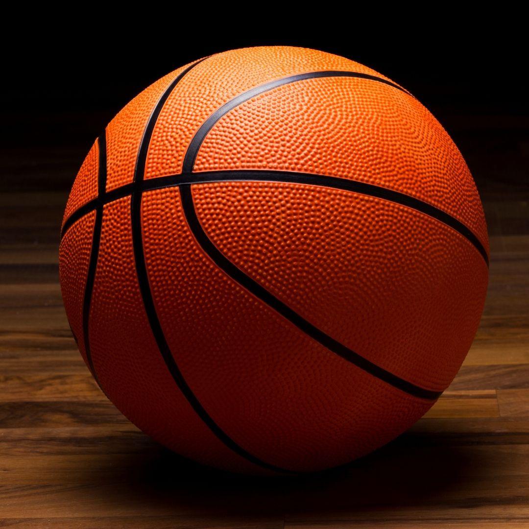 A basketball sits on a wooden floor