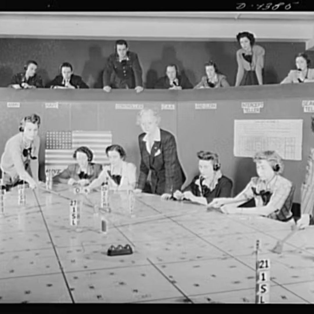 Women sit around a table looking at maps. 