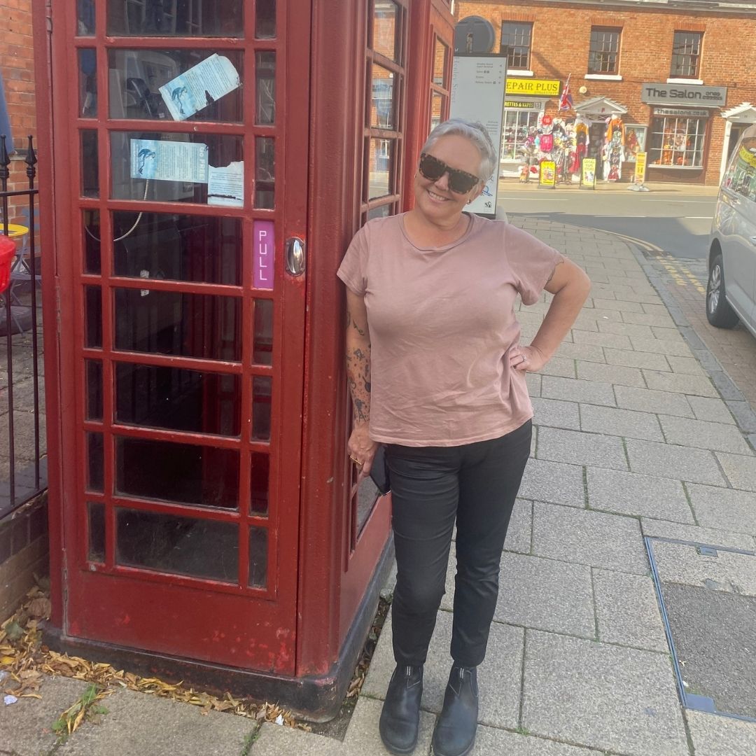 Nicci Guagliardo stands in front of a red phone booth