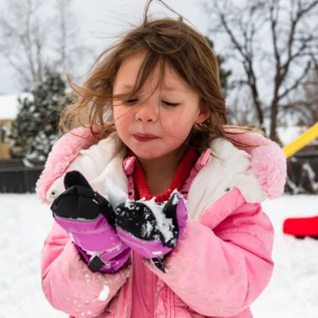 A child holds snow in their hands. 