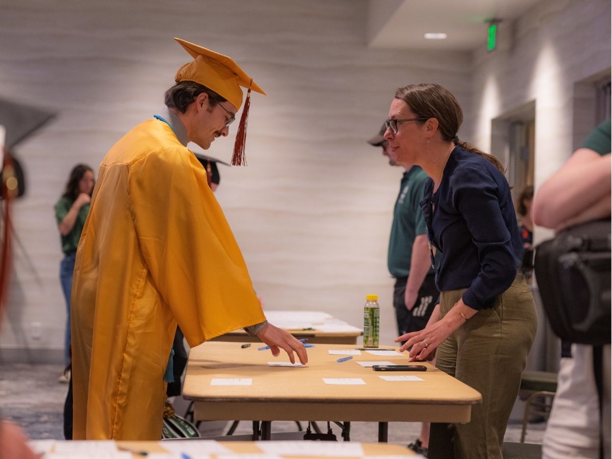 A volunteer helps a graduate with their name card. 