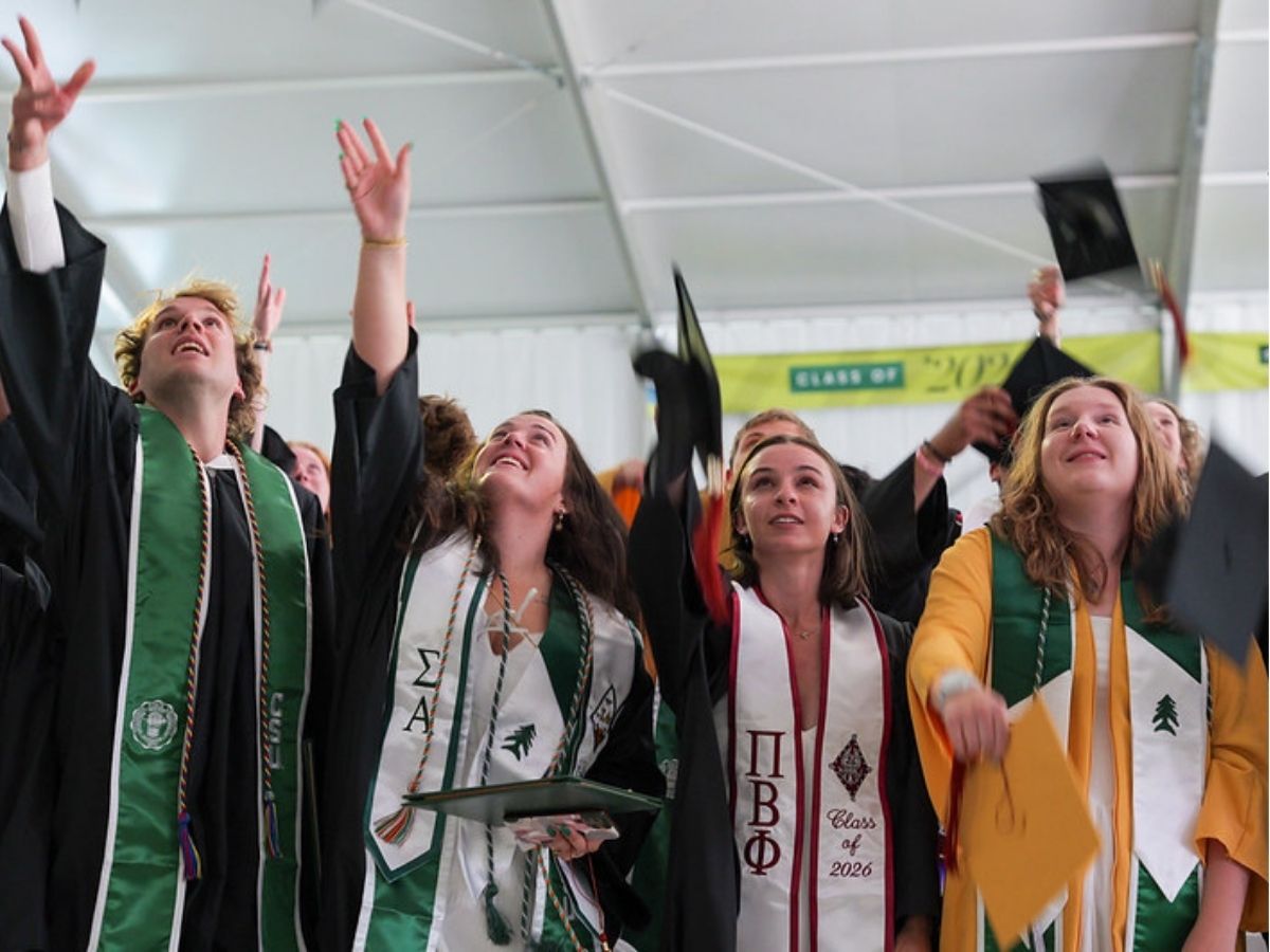 A group of graduates throw their mortar boards in the air. 