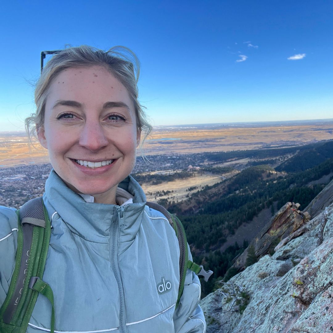 Rebecca Niemiec stands at the top of a mountain.