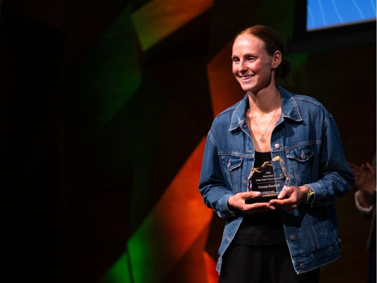 A student holds an award and smiles for the camera