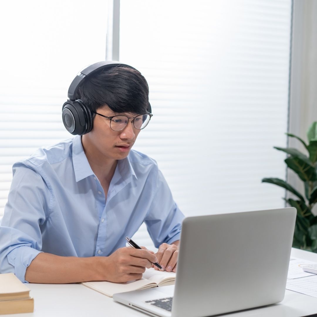 A student looks at a laptop while wearing headphones